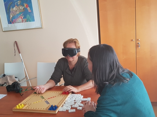 Udeleženka igra igro človek ne jezi se prilagojeno za slepe s temnimi očali