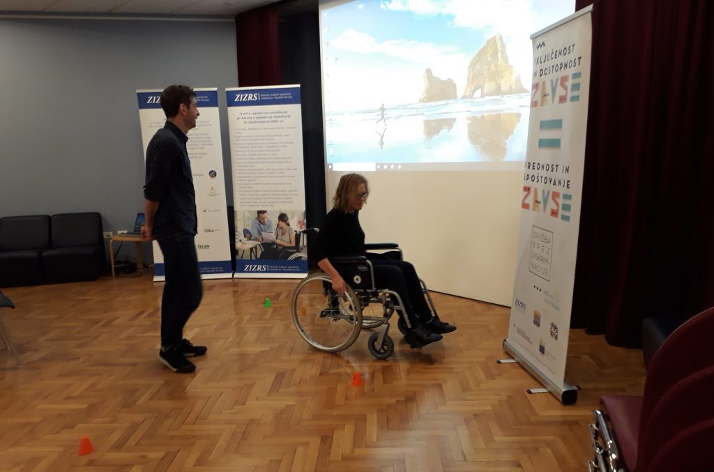 Udeleženka se preizkuša v vožnji med ovirami z invalidskim vozičkom