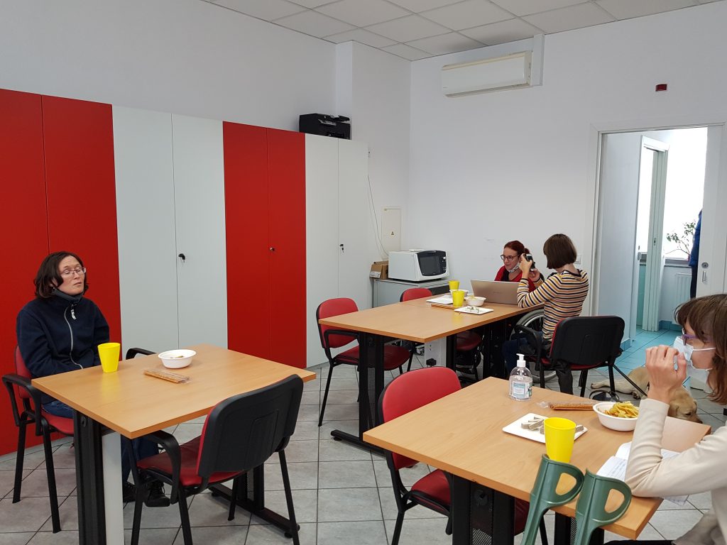 Ena od udeleženk, sede za mizo, deli svoje mnenje o knjigi, ostali poslušajo.