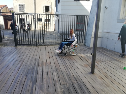 Udeleženka vozi invalidski voziček med postavljenimi stožci