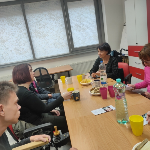 Udeleženci za mizo poslušajo gostjo