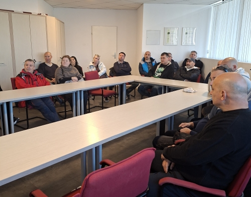 Zaposleni Maproma za mizami v obliki črke U poslušajo predstavitev