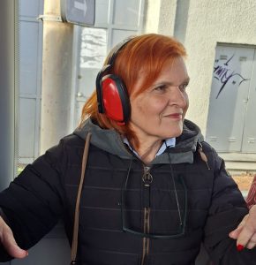 Udeleženka z delavskimi slušalkami, ki zmanjšajo hrup na avtobusu