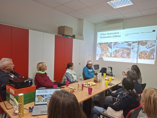 Udeleženci sedijo za mizami in poslušajo o sedmem dnevu hoje po Caminu