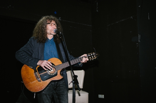 Adi Smolar poje in igra kitaro na odru