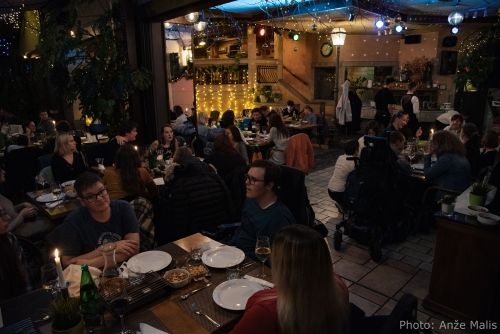 Udeleženci večerje se pogovarjajo za mizami