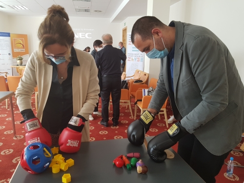 Udeleženka in udeleženec z boksarskimi rokavicami spoznavata kako je, če imamo težave s fino motoriko