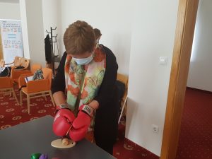 Udeleženka z boksarskimi rokavicami reže leseno gobo z lesenim nožem