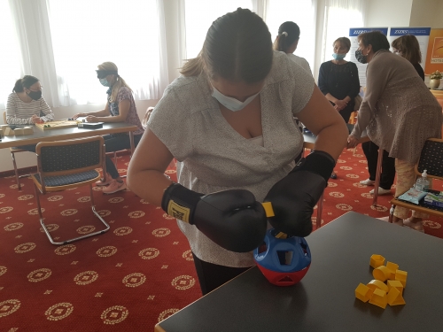 Udeleženka z rokavicami vstavlja različne like v primerne odprtine