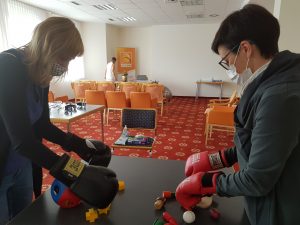 Udeleženki z boksarskimi rokavicami režeta leseno zelenjavo in vstavljata različne like v odprtine
