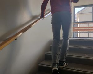 Dijak s temnimi očali in belo palico gre po stopnicah šole