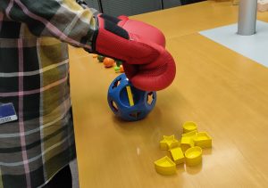 Udeleženka preizkuša vajo za simulacijo težav s fino motoriko
