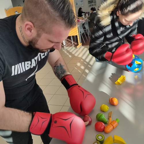 Udeleženca z boksarskimi rokavicami spoznavata težave z motoriko rok