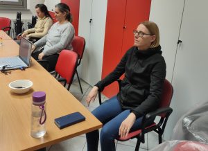 Udeležneci izvajajo vajo z izstegnjenima rokama pred seboj