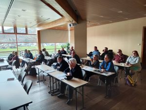 Udeleženci spremljajo program za mizami