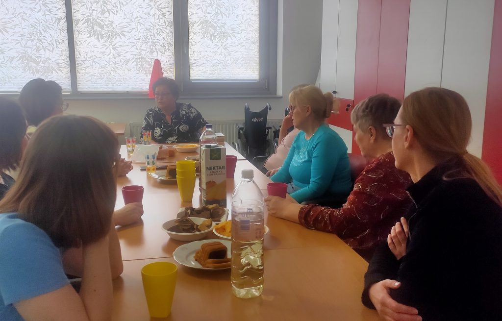 Ksenija na čelu mize udeležencem pripoveduje o svojem življenju.