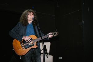 Adi Smolar poje in igra kitaro na odru